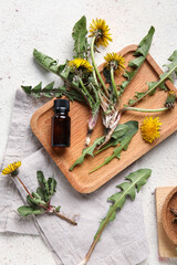 Yellow dandelions with cosmetic bottle, wooden board and napkin on white background