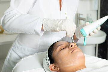 Naklejka premium Latina woman with skin treatment, Hispanic doing laser hair removal underarms, dermatology clinic in Costa Rica. Skin treatment, acne and hair removal. Copy space for advertising and blurred backgroun