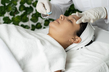 Latina woman with skin treatment, Hispanic doing laser hair removal underarms, dermatology clinic in Costa Rica. Skin treatment, acne and hair removal. Copy space for advertising and blurred backgroun