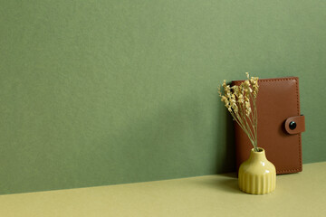 Dairy notebook and dry flower on desk. khaki green background