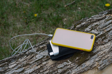 A portable charger charges the smartphone. Power Bank with cable against the background of wood
