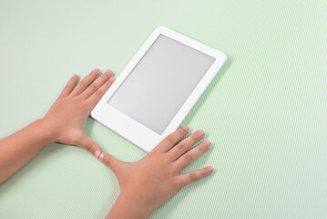 Ebook reader over green background - being held by the hand of a child