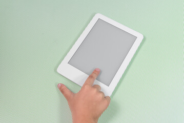 Ebook reader over green background - being held by the hand of a child