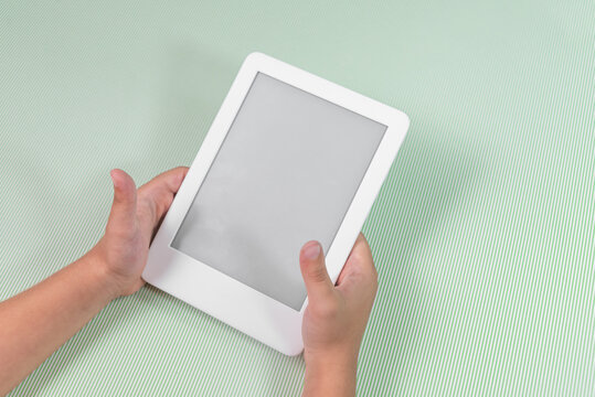 Ebook reader over green background - being held by the hand of a child