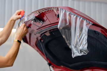 Closeup master Installs vinyl film for protect paint body hood red car