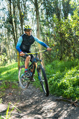 Fototapeta na wymiar Man with helmet and goggles jumping on his mountain bike in a forest