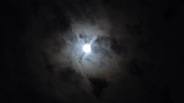 Quick shot of the bright moon at night with the clouds rushing by. time lapse in 4k