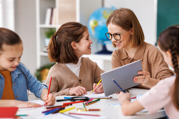 Woman with tablet teaching children at school