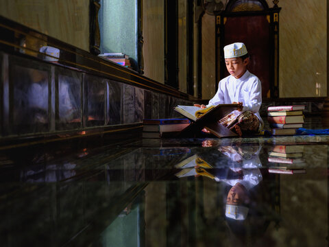 muslim student studying and reading Islam holy quran book in mosque