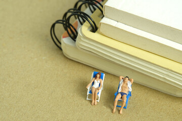 Miniature people toy figure photography. Office work break concept, Men and girl relaxing at beach...