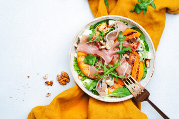 Summer salad bowl with sweet grilled peach, jamon, soft cheese, walnuts and fresh arugula on white...