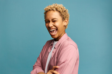 Young vibrant laughing blonde African female with nose ring winking keeping mouth opened widely,...