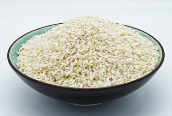 Uncooked dry rice in a bowl isolated on white background.