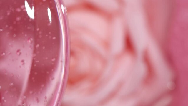 Transparent pink cosmetics serum fluid gel, vertical beauty cream, rose flower 