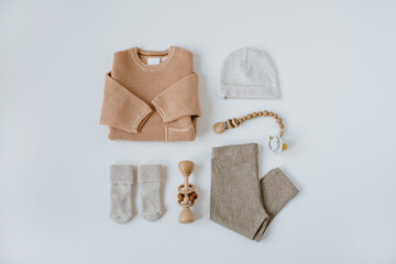 Flatlay aesthetic Scandinavian newborn baby clothes, accessories, toys collage on white background. Trendy elegant neutral pastel colour infant wear. Top view