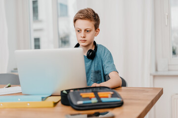 schoolboy sitting in front of a laptop doing his homework
