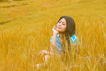 Young woman sitting on dried grass at the autumn