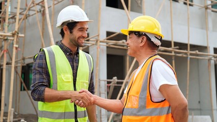 Professional male engineer foreman with white helmet closing blueprint of structure talking and...