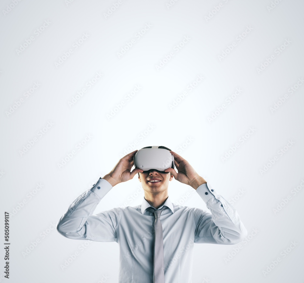 Poster virtual reality concept with young businessman gets new emotions in vr glasses on abstract light gre