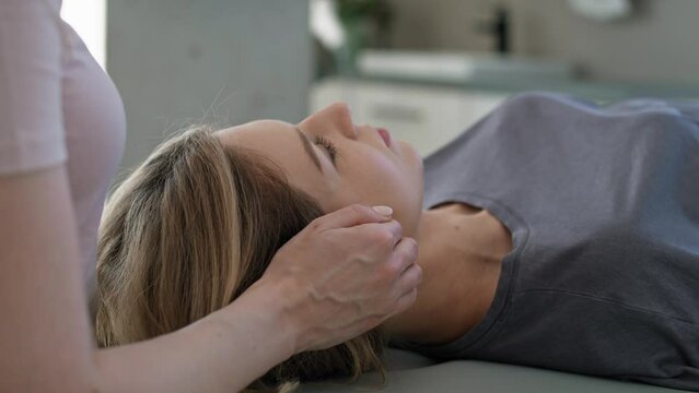 Female physical therapist massaging her patient around head and neck. Shot with RED helium camera in 8K.    