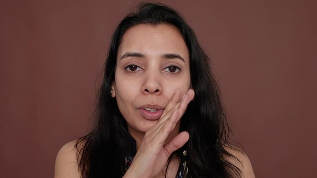 Portrait of indian woman sharing overheard secret in studio, spreading confidential information as rumor, being nosy. Telling secret about someone, unbelievable gossip from private conversation.