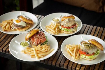 Various gourmet burgers selection on restaurant wood table