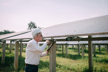 Young engineer checking with a tablet the sun's operation and cleanliness on the field of photovoltaic solar panels at sunset. Concept: renewable energy, technology, electricity,