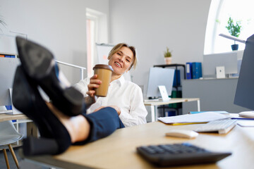 Business woman relaxing during coffee break putting legs on the desk