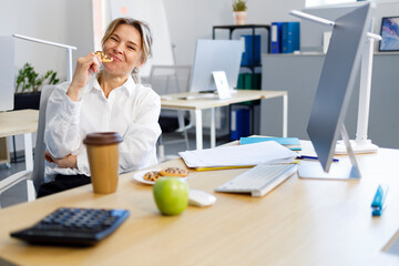 Business woman eating cookies at work