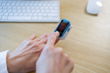 Office worker using fingertip oximeter at office