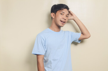 Portrait of standing asian young man wearing blue t-shirt with happy face, isolated background
