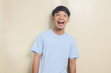 asian man in blue shirt looks happy on isolated background