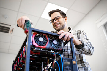 An intelligent caucasian man using screwdriver to build cryptocyrrency bitcoin rig for mining.