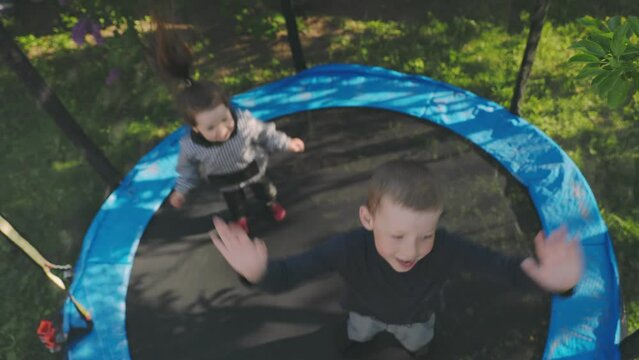 two children have fun jumping on a trampoline top view