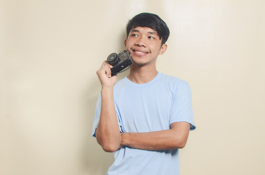 Portrait of happy asian young man holding camera on isolated background