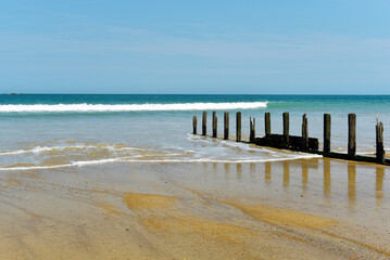 Fototapeta na wymiar Brises-lames sur la plage à marée montante