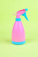 Bright pink cleanser sprayer on green background. Pink garden sprinkler vertical photo