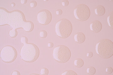 Round drops of transparent gel serum on pastel pink background. Skincare cosmetic product texture