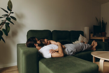 young woman hugging a young man lying on the couch. young happy couple hugging on the sofa.	
