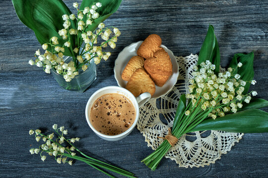 cup of coffee and lilies of the valley on wooden background