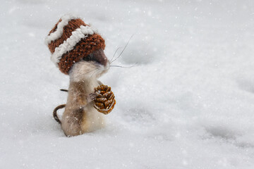 Needle felted mouse wearing a woolly hat and sitting in the snow