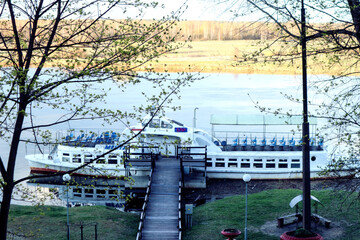Fototapeta premium View from the stairs to a small motor ship on a spring day, blue sky background, spring landscape