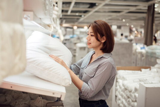 An Asian woman is choosing a pillow at the mall.