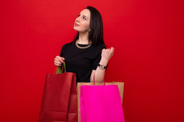 A young woman with colorful shopping bags on a red background