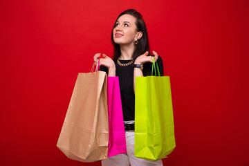 Fototapeta na wymiar A young woman with colorful shopping bags on a red background