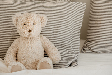 Teddy bear sits on a bed.