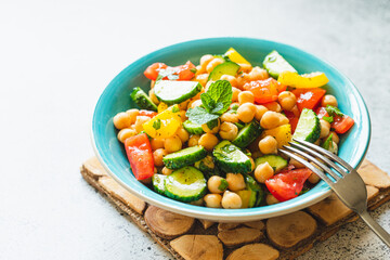 Chickpea salad with tomatoes, cucumber, parsley, onions in a plate, selective focus. Healthy vegetarian food, oriental and Mediterranean cuisine. Chick peas salad
