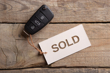 Car auction Sold out concept. Vehicle security key with tag on the wooden background