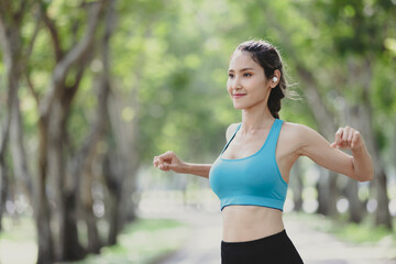 Young athletic woman stretching herself in park and using bluetooth headphones listen music. Portrait of beautiful sportswoman.