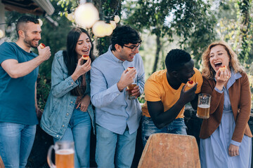 people having fun - happy friends playing with food - glamping party with small pizzas and beer - holiday concept